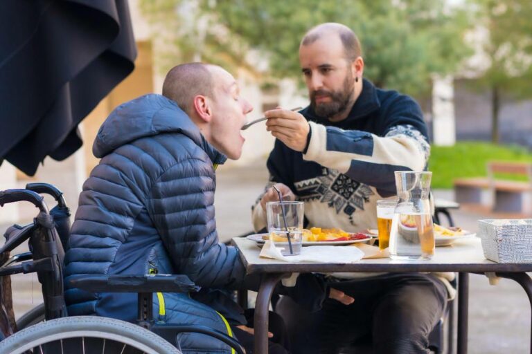 personne-handicapee-mangeant-terrasse-restaurant-ami-aidant-manger